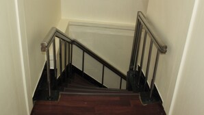 A wooden staircase with metal railings leading to a landing. - Dongdaemun Guest House (Seoul)