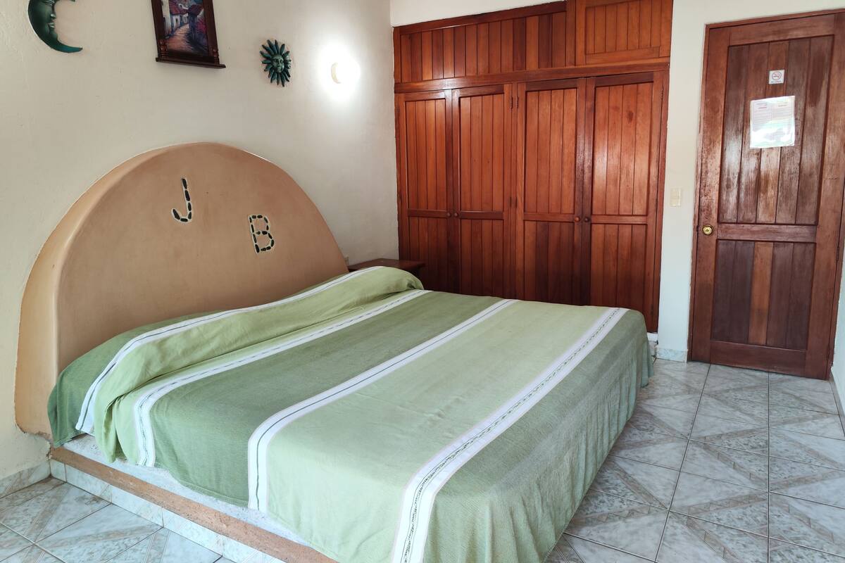 Ein Schlafzimmer mit Bett, Holzschrank und Tür.