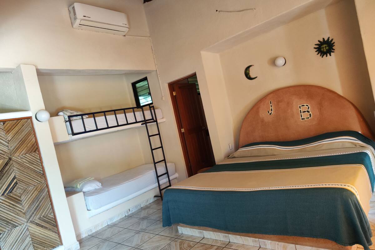 Ein Zimmer mit Etagenbetten, einem Holzkopfteil, einer Wand-Klimaanlage und einer Wand mit Muster.
