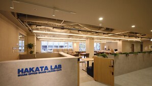 A modern office space with cubicles, a lounge area, and a kitchenette.