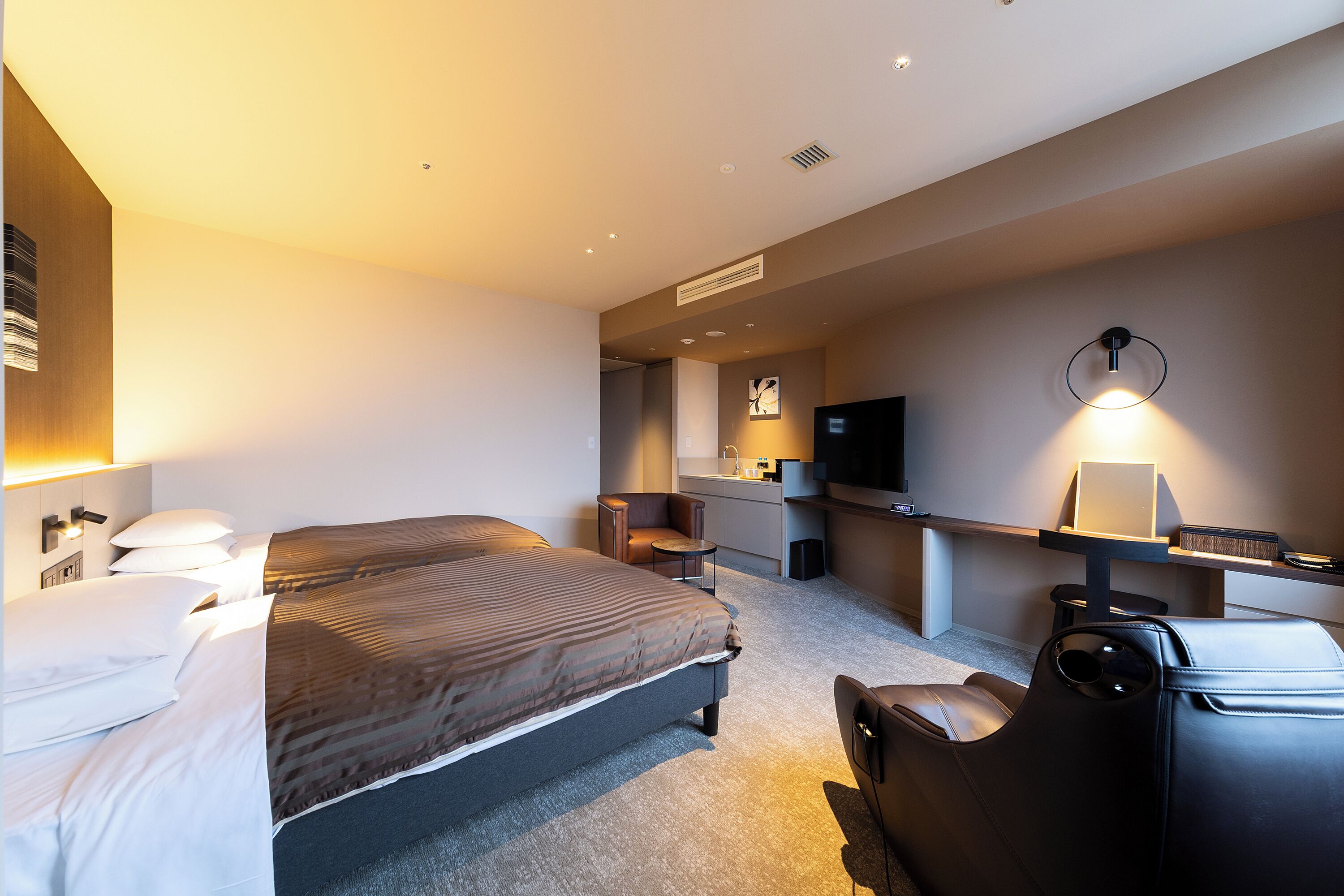 Habitación de hotel con una cama grande, un escritorio, una silla y un televisor.