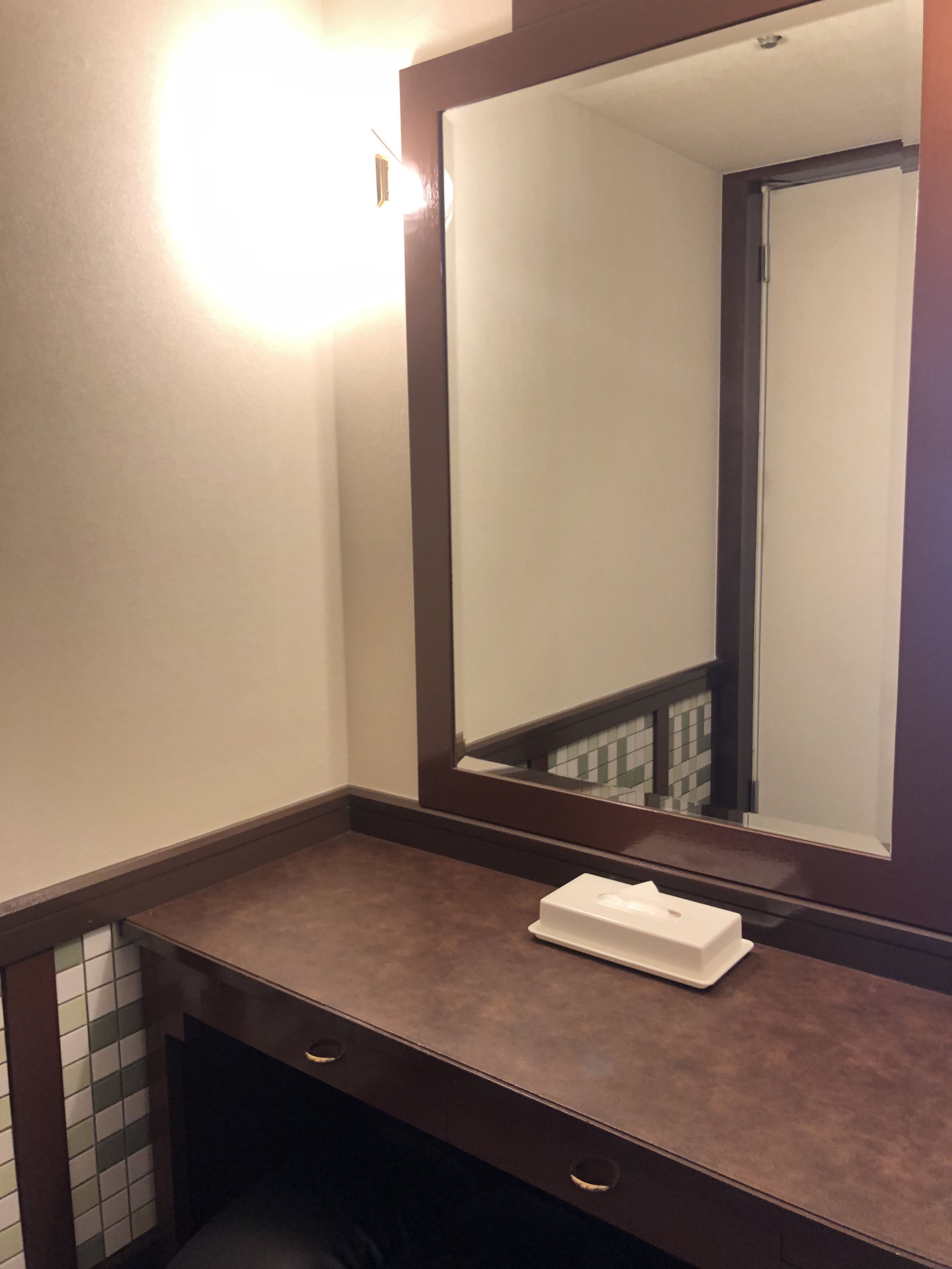 A bathroom with a large mirror, a towel, and a tiled wall.