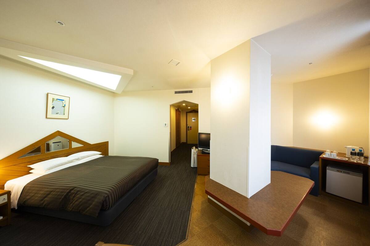 Une chambre d’hôtel comprenant un lit, un bureau, une chaise, une petite kitchenette et une salle de bain.