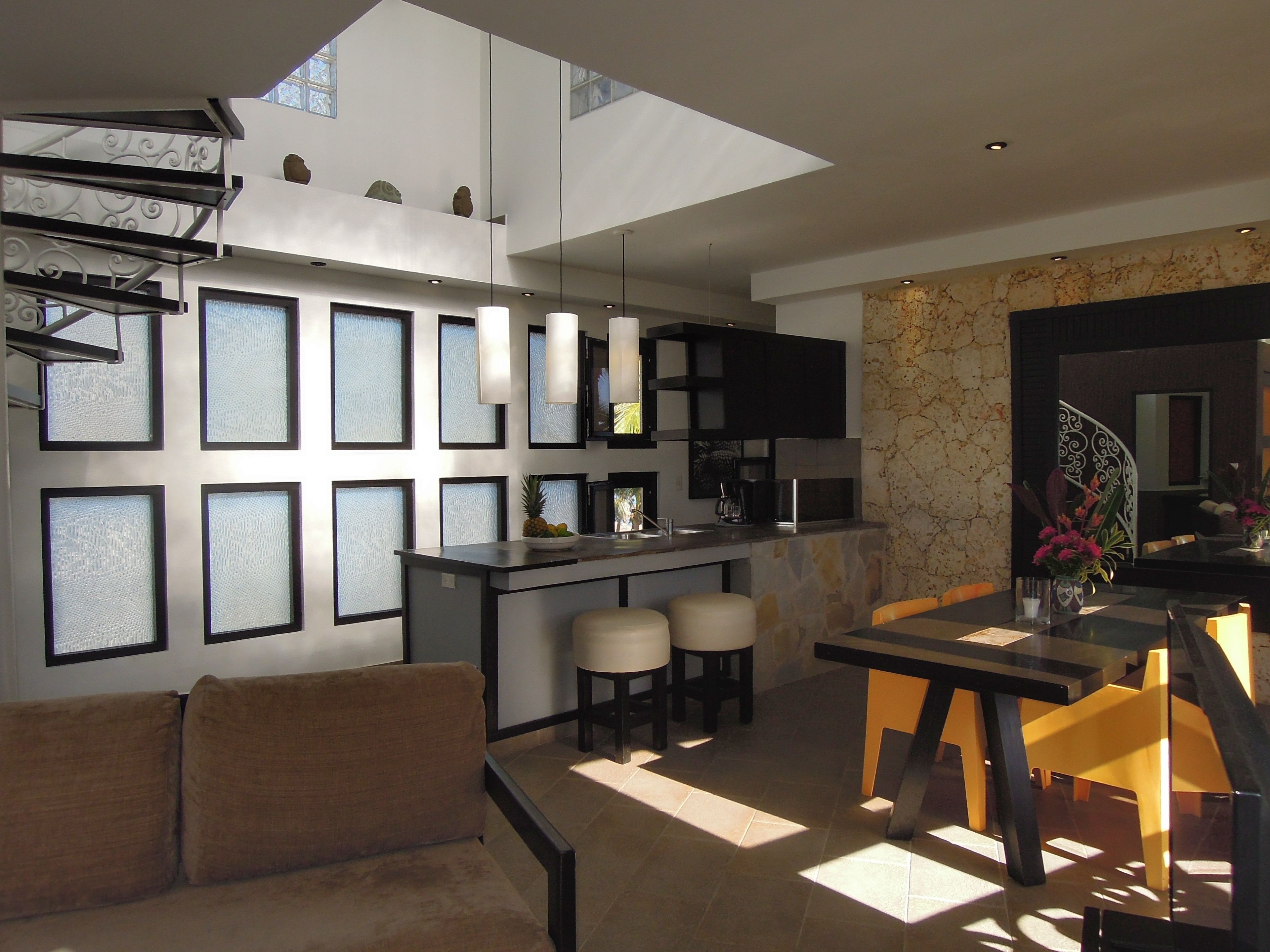Una cocina moderna con una isla central, taburetes de bar y un área de comedor con mesa y sillas.