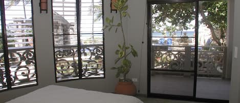 A bedroom with a bed, a potted plant, and a sliding glass door leading to an outdoor area.