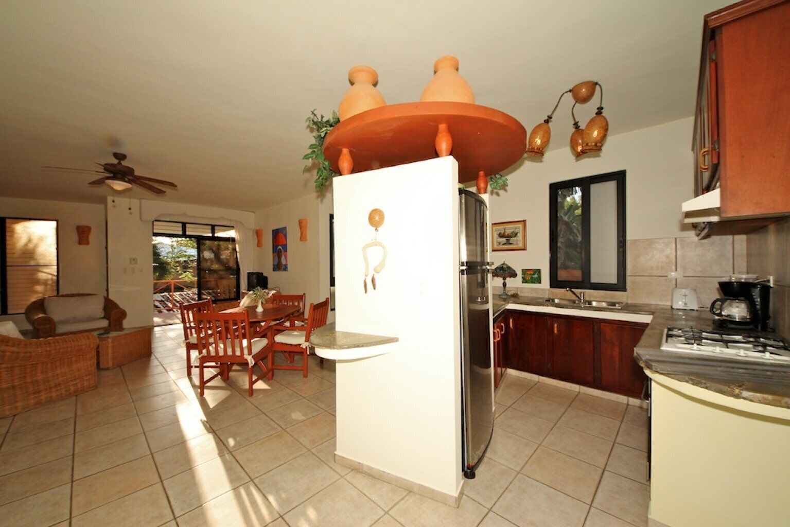 A kitchen with a refrigerator, stove, and dining area with chairs and a table.