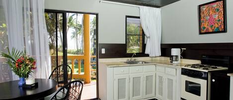 A compact kitchen with a sink, stove, and cabinets. There is a dining area with a table and chairs.