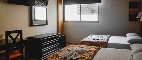 Une chambre avec deux lits, une commode, une chaise et une fenêtre avec des stores.