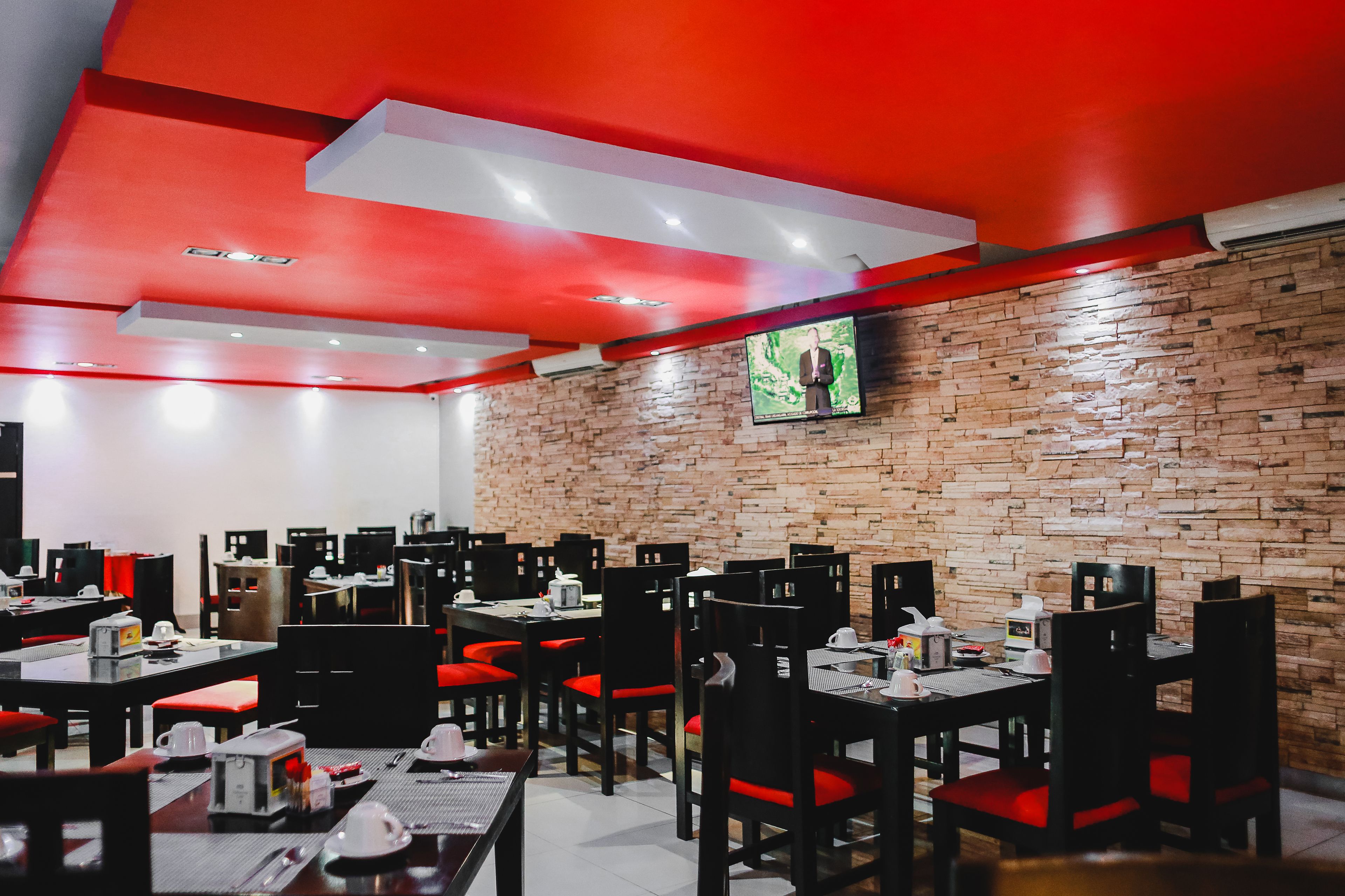 A restaurant with brick walls, red ceiling accents, and multiple tables with chairs.