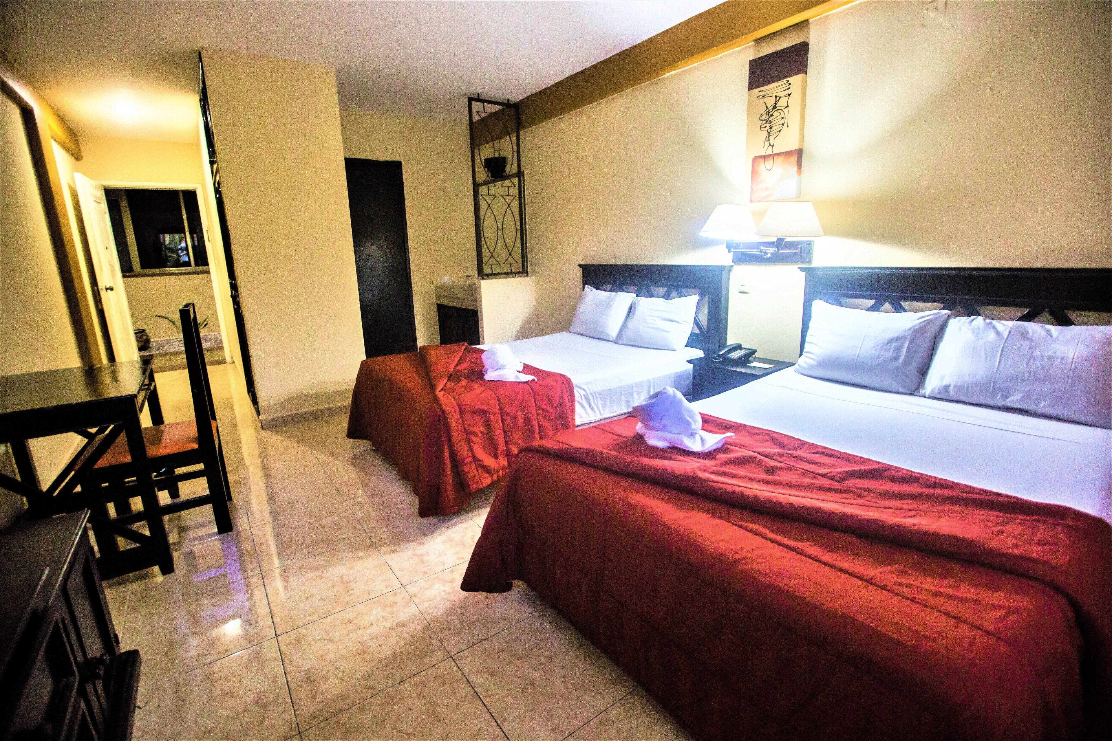A hotel room with two beds, a desk, and a chair.