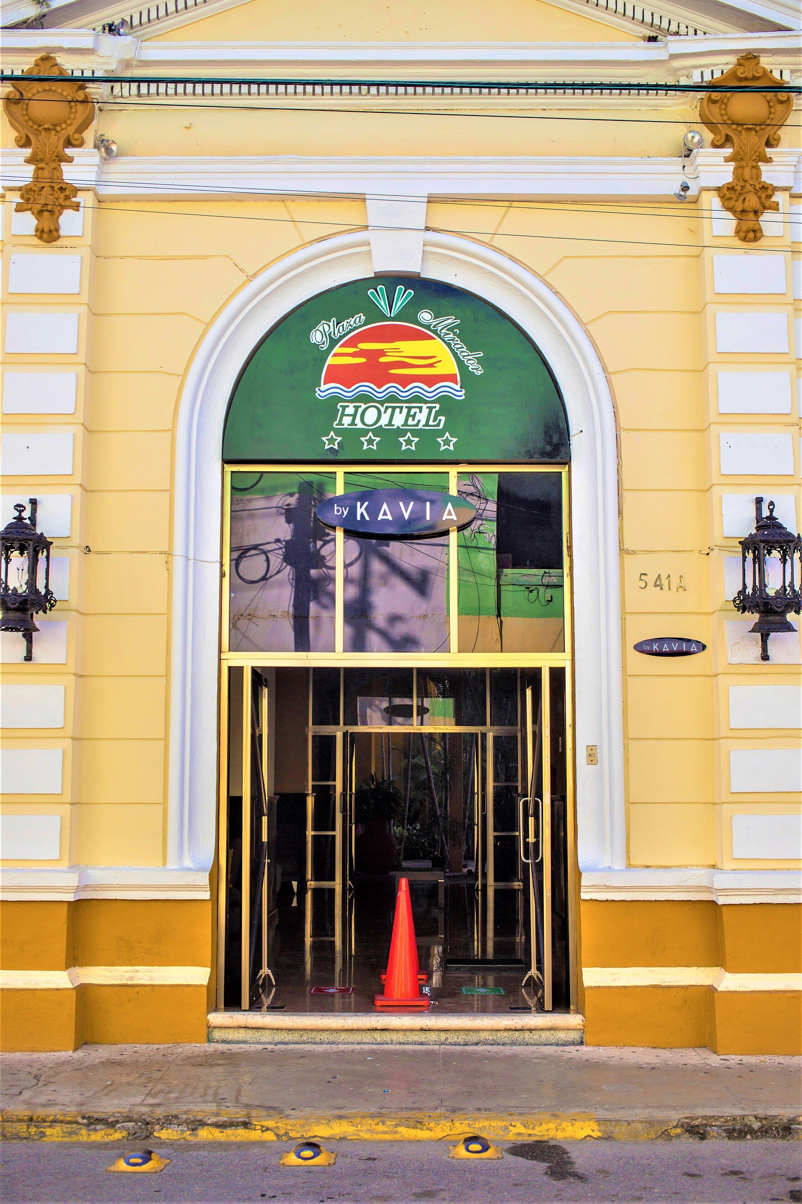 Una entrada de hotel con un toldo verde, un letrero que dice "Hotel Kavia" y el número "541A" en la pared.