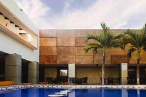 Zona de piscina interior con asientos y palmeras.