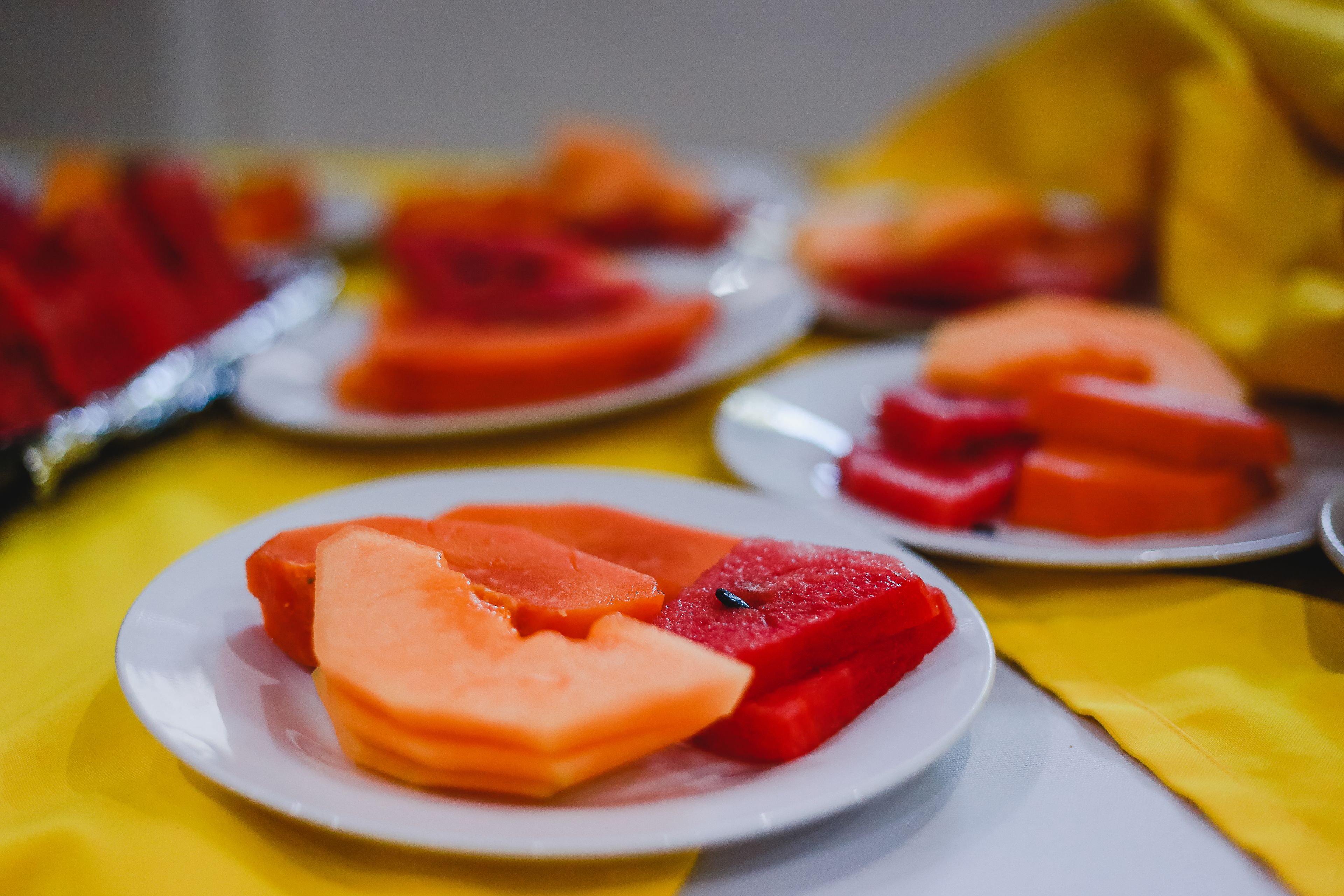 A table with plates of sliced cantaloupe and watermelon.