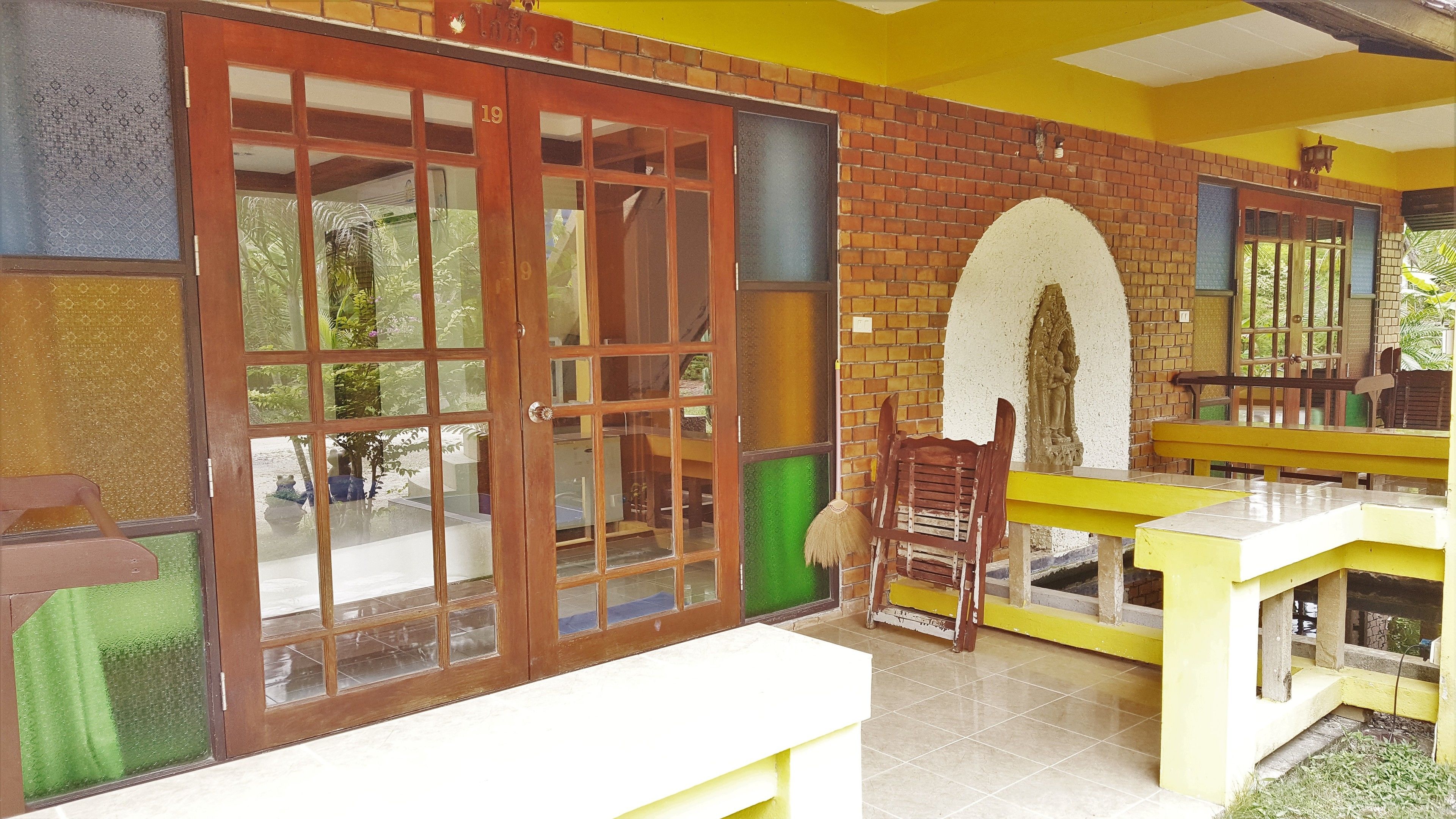 A room with a large sliding glass door, a brick wall, a yellow bench, and a small table.