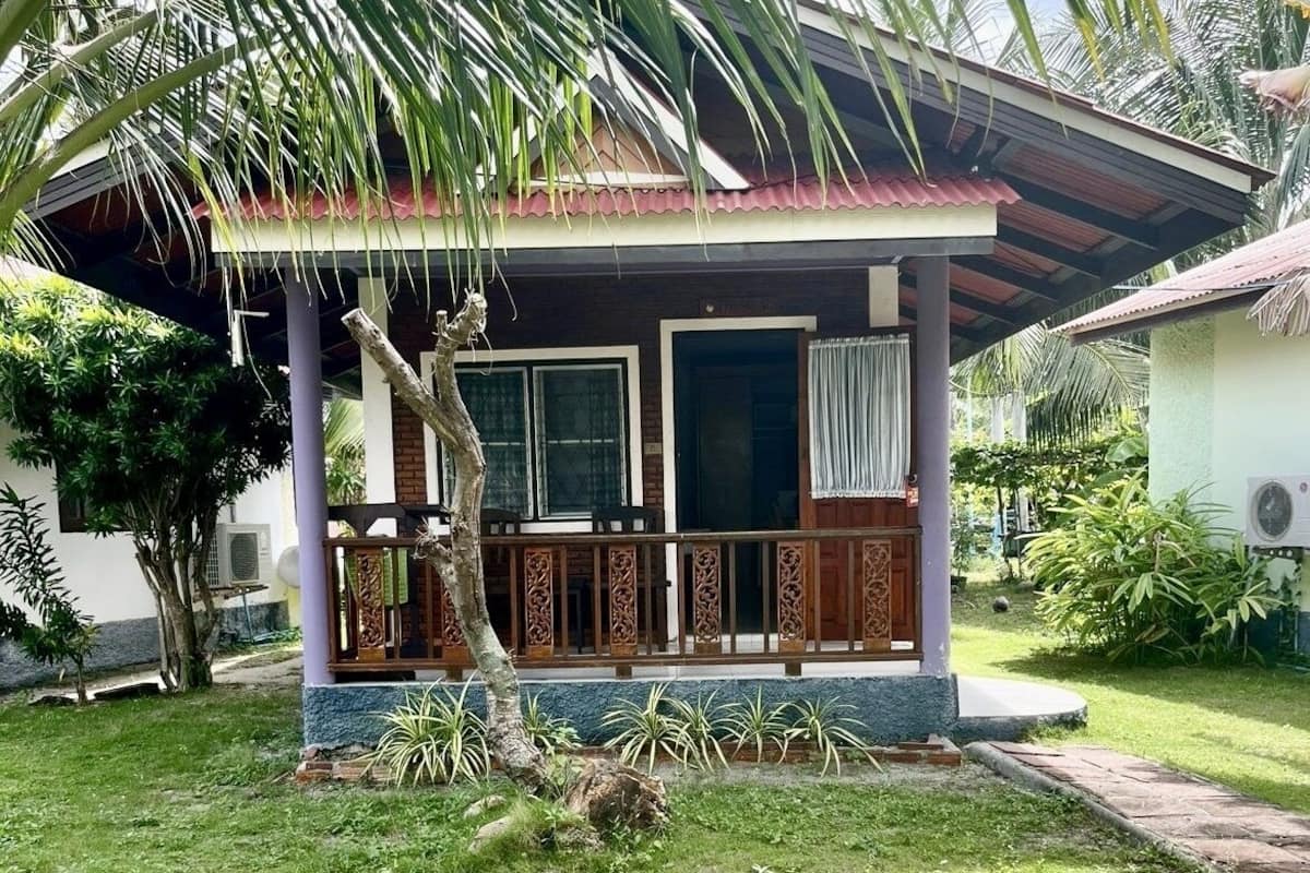 A small, single-story house with a porch and a covered patio area.