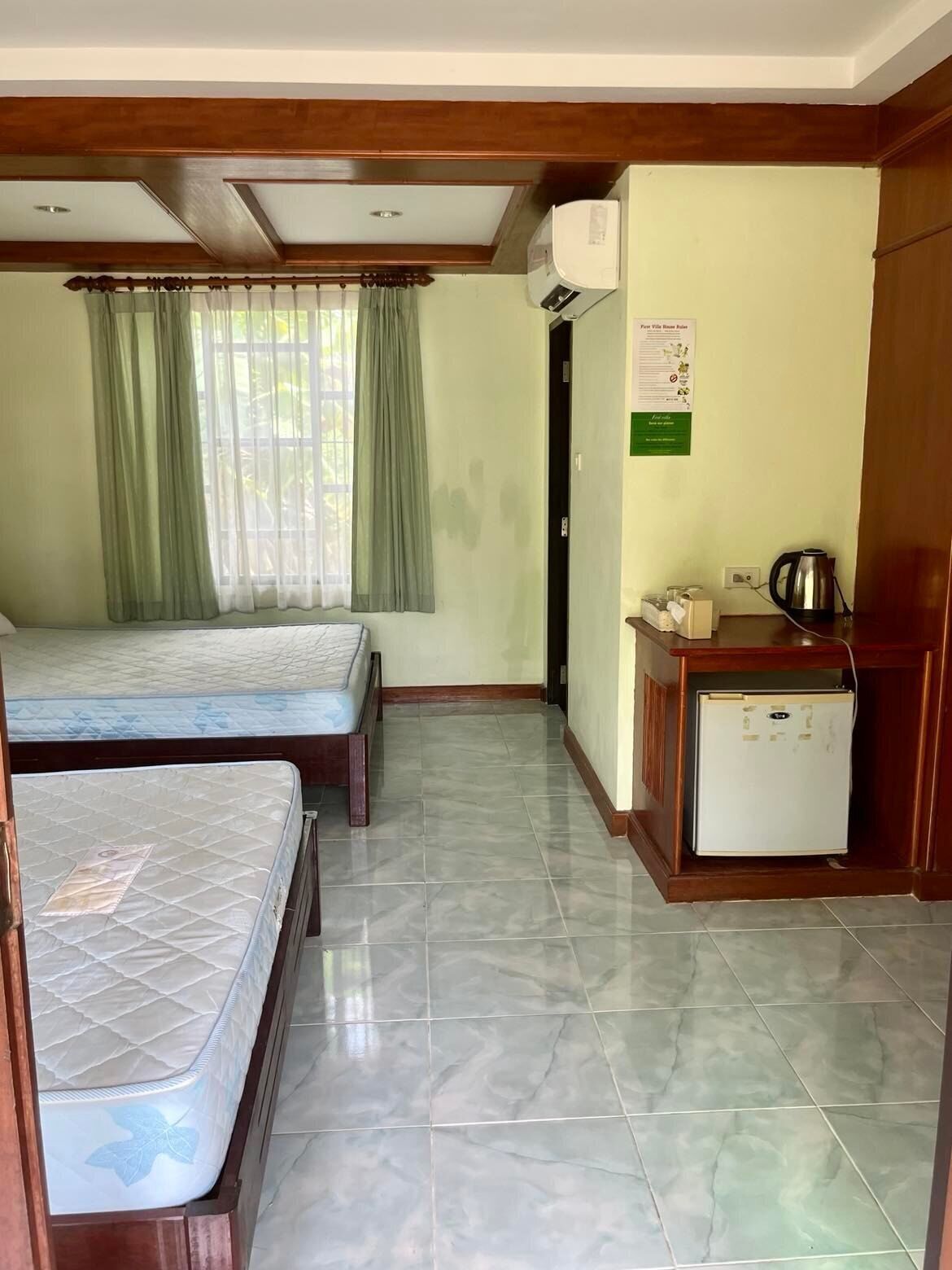 A room with two beds, a small kitchenette, and a door leading to another room.