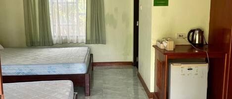 A room with two beds, a small kitchenette, and a door leading to another room.