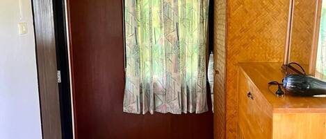 A room with a wooden wardrobe, a tiled floor, and a curtain with a geometric pattern.