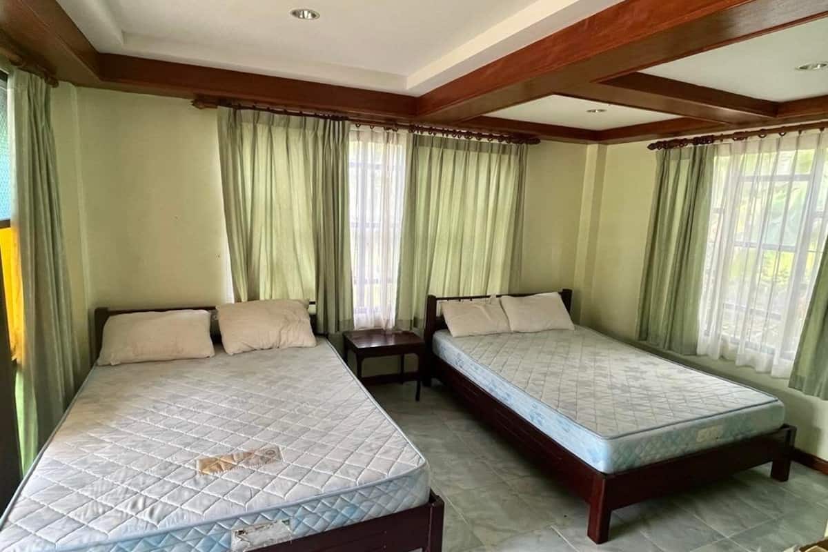 A room with two beds, a small table, and curtains.