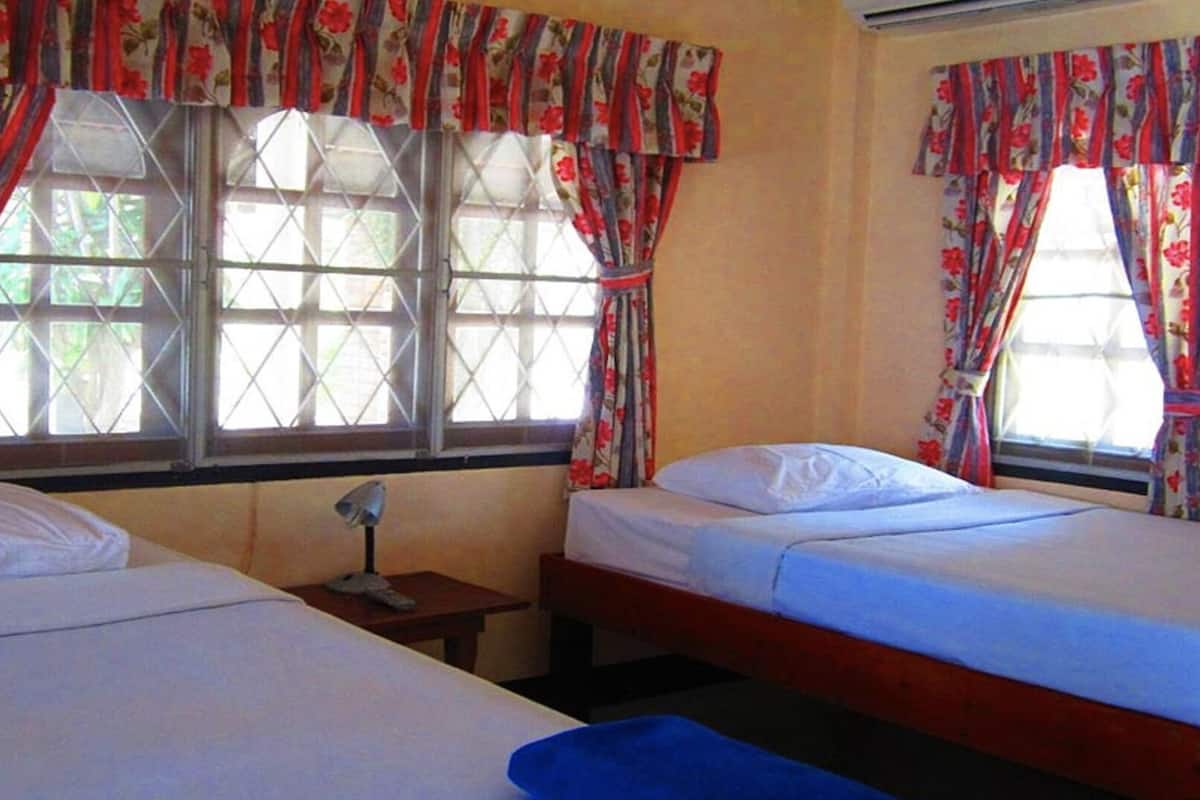 A room with two beds, a small table, and a window with curtains.