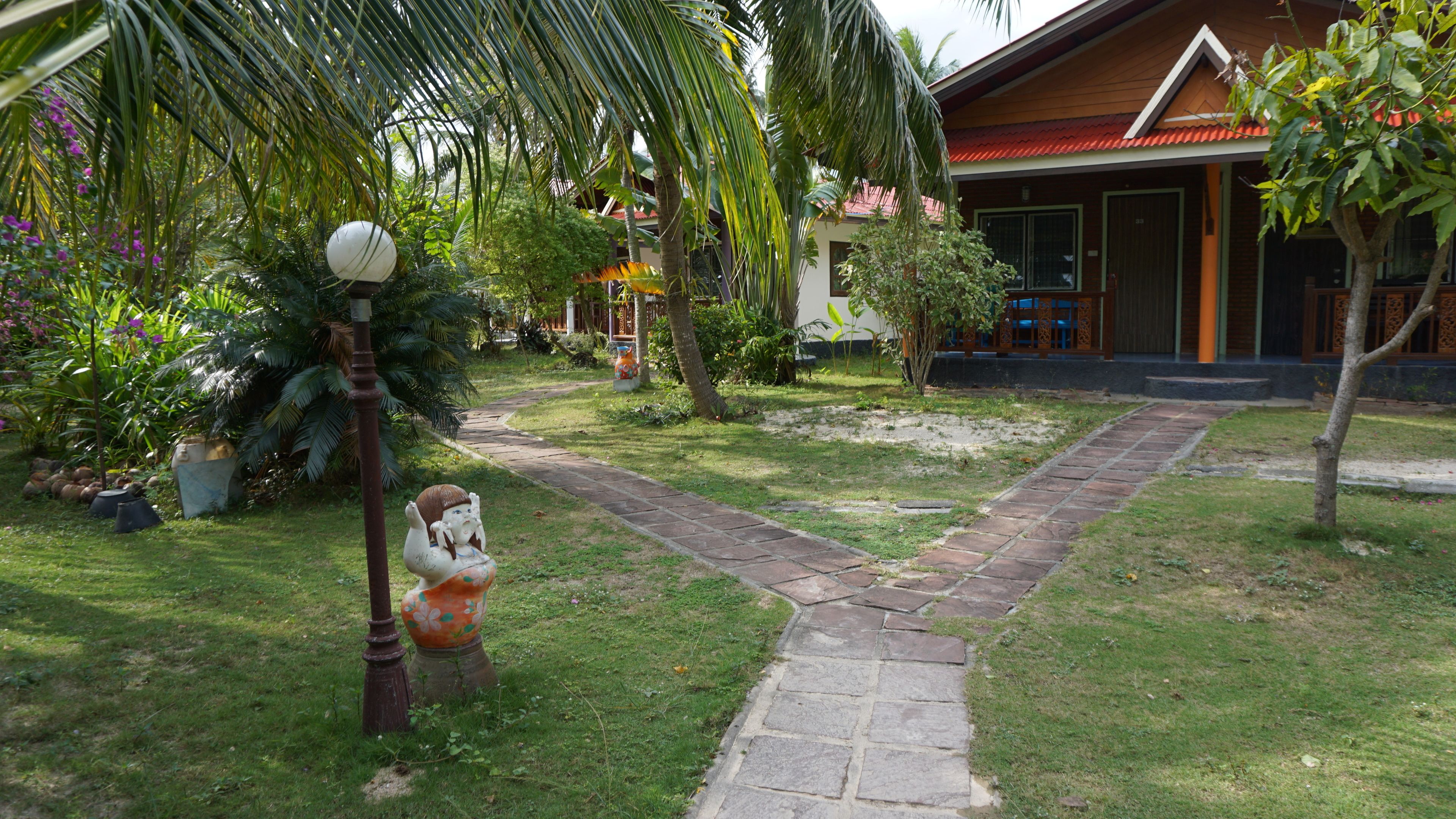 A garden pathway leading to a building with a tiled roof and traditional design.