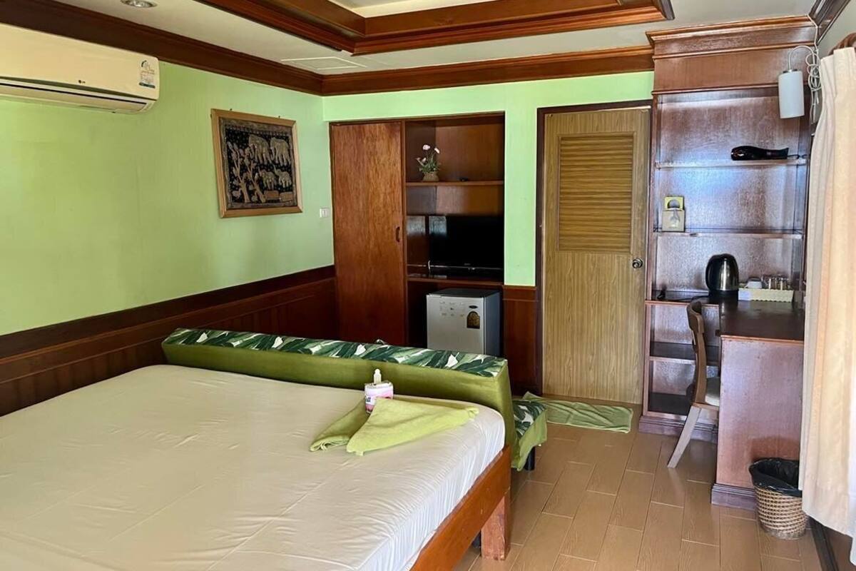 A hotel room with a bed, a small desk, a wardrobe, a television, and a bathroom.