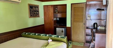 Una habitación de hotel con cama, un escritorio pequeño, armario, televisor y baño.