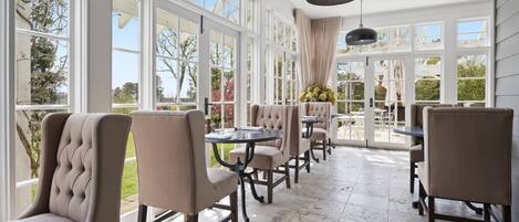 A spacious indoor area with large windows, comfortable seating, and a ceiling light fixture.