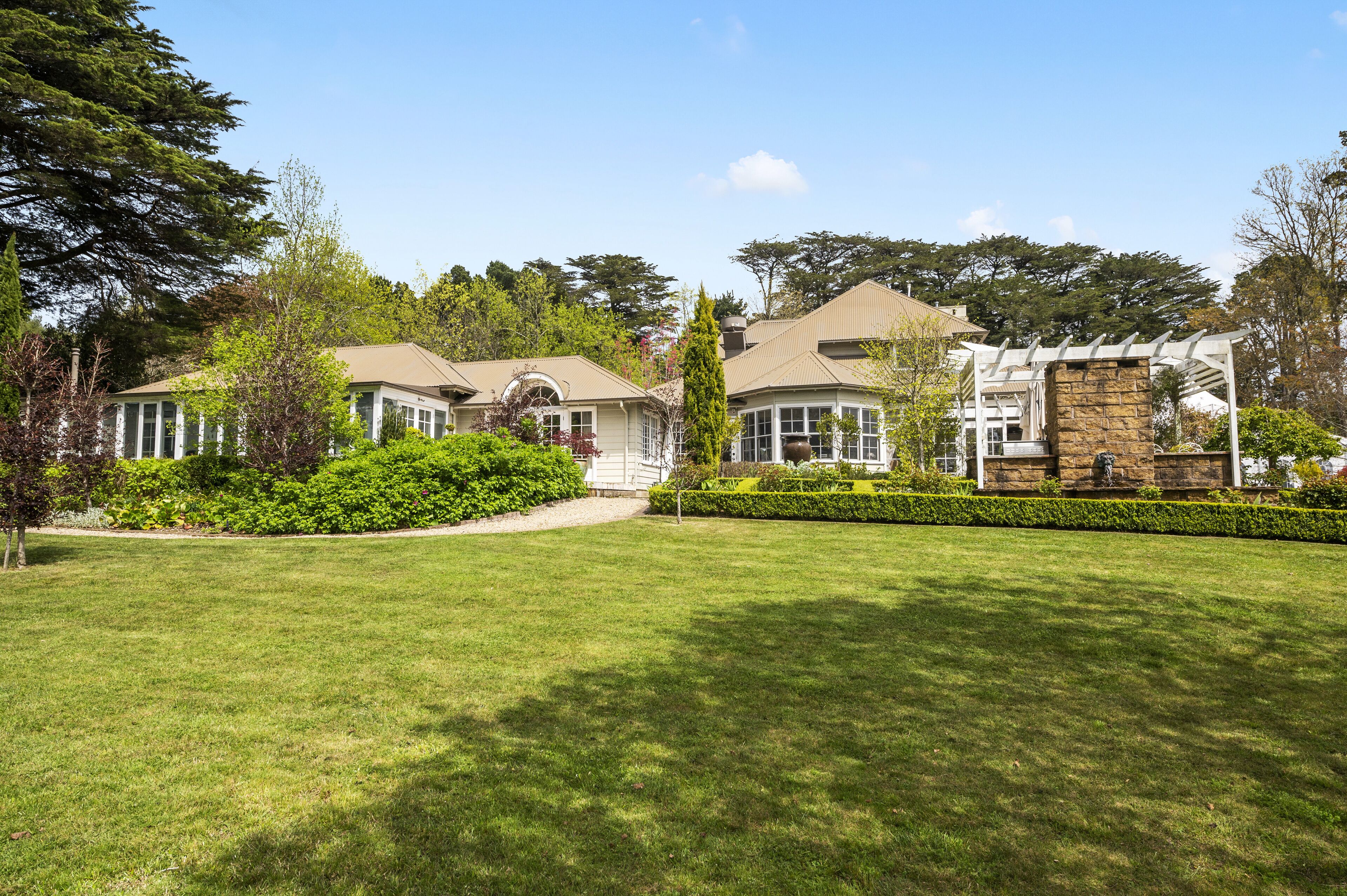 A residential property with a well-maintained lawn, a stone patio, and a pergola.