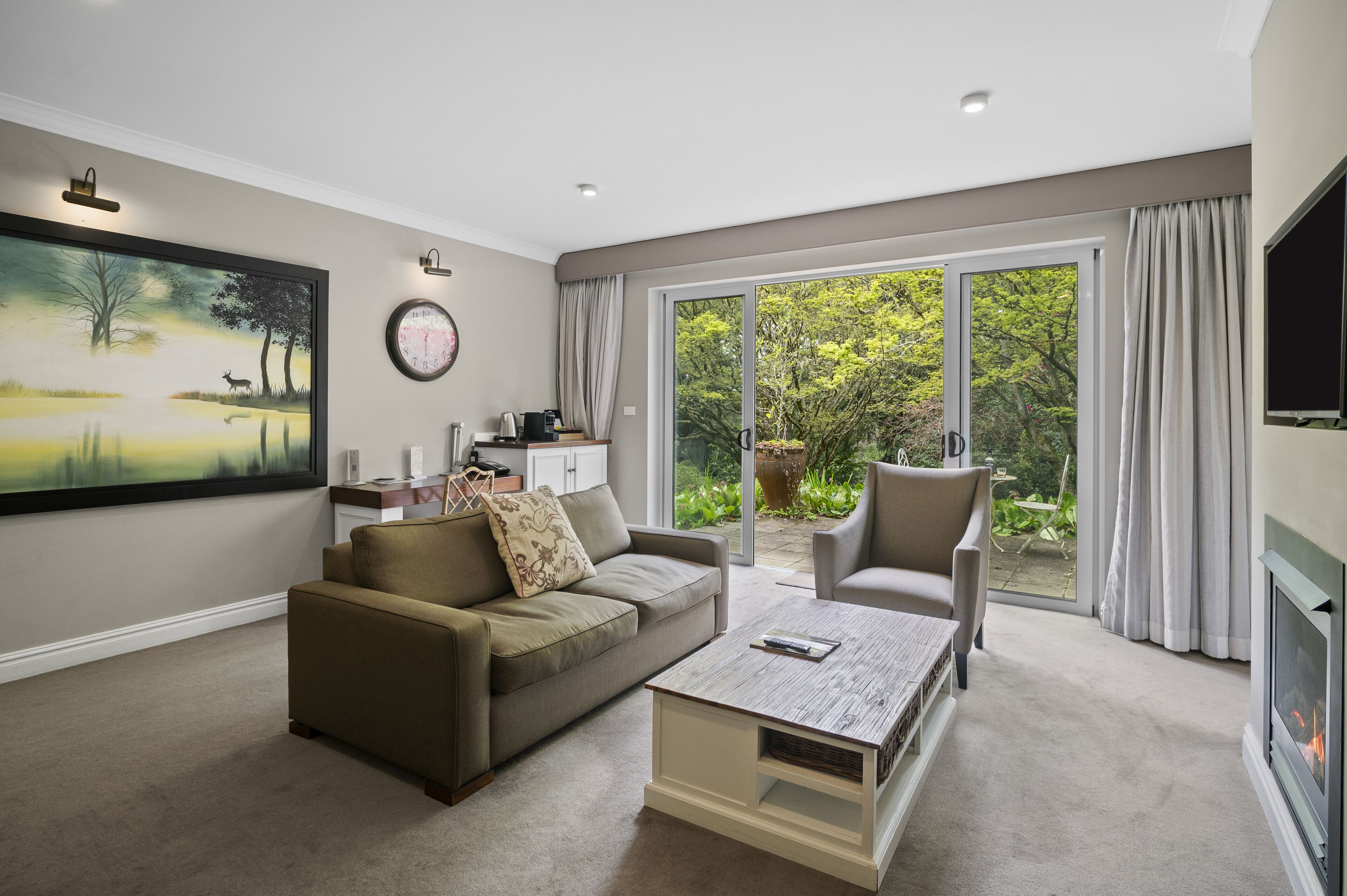 A modern living room with a sofa, armchair, coffee table, and a fireplace.