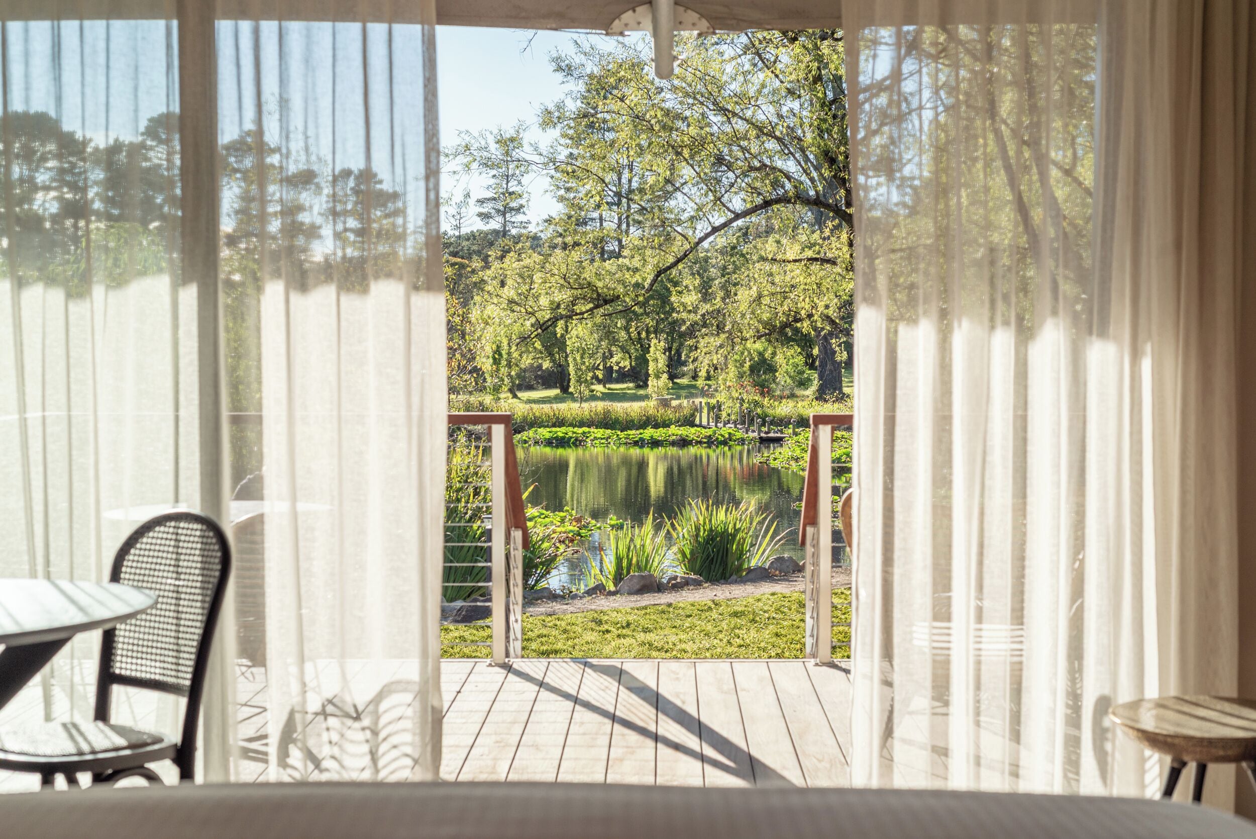 A covered outdoor deck with a view of a pond and trees.