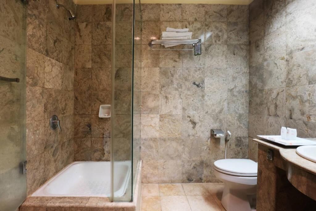 Un bagno moderno con doccia vetro, un water e un lavandino.