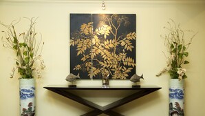 Un comptoir d’accueil agrémenté de deux vases de fleurs, d’une œuvre d’art aux couleurs noir et or, et doté d’un design moderne.