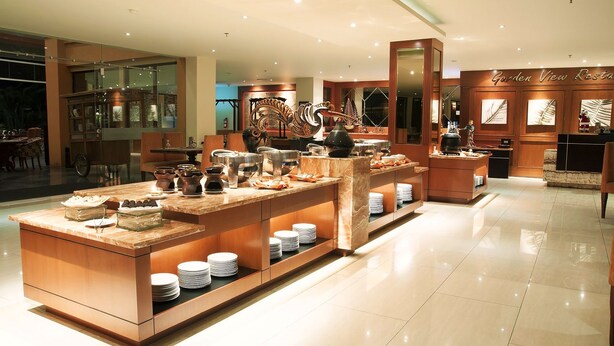 Un restaurant moderne doté d’un buffet central, d’une décoration en bois et d’une enseigne indiquant « Restaurant avec vue sur le jardin ».