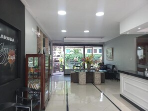 A hotel lobby with a reception desk, seating area, and a glass door leading outside. - Mindu Park Hotel (Manaus)