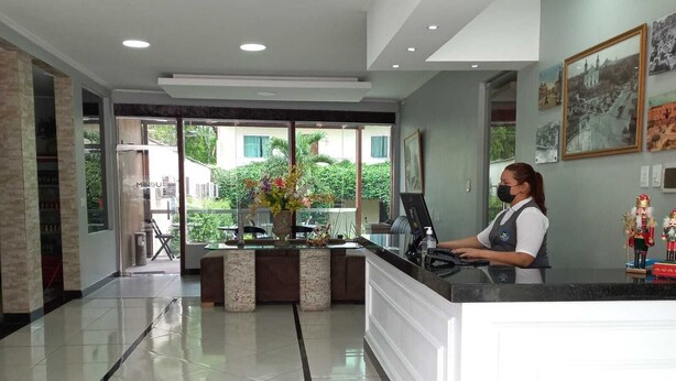 A reception area with a counter, a computer, and a decorative vase with flowers.