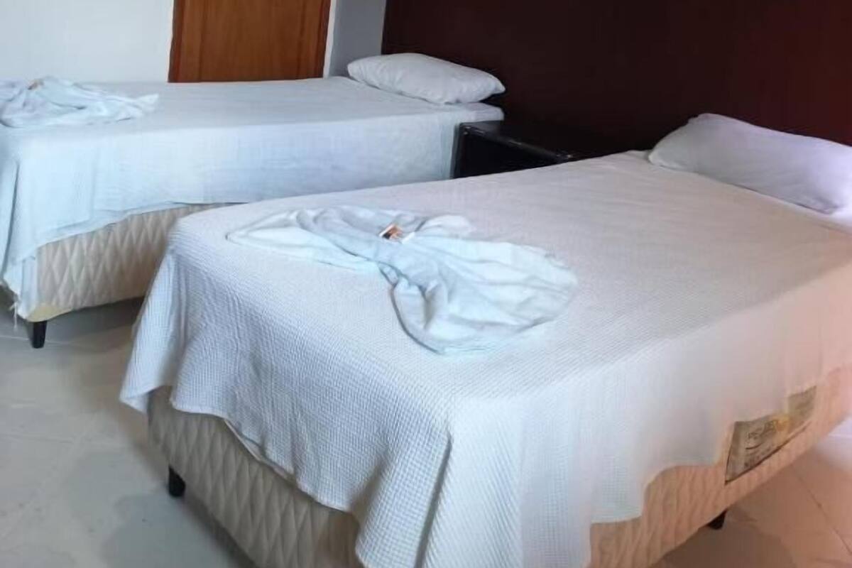 Una habitación de hotel con dos camas individuales, una puerta de madera y un cuadro enmarcado en la pared.