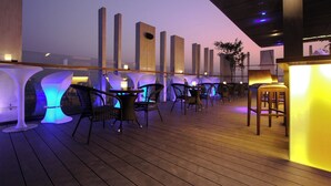 An outdoor seating area with tables and chairs, illuminated by ambient lighting. - Amari Dhaka (Dhaka)