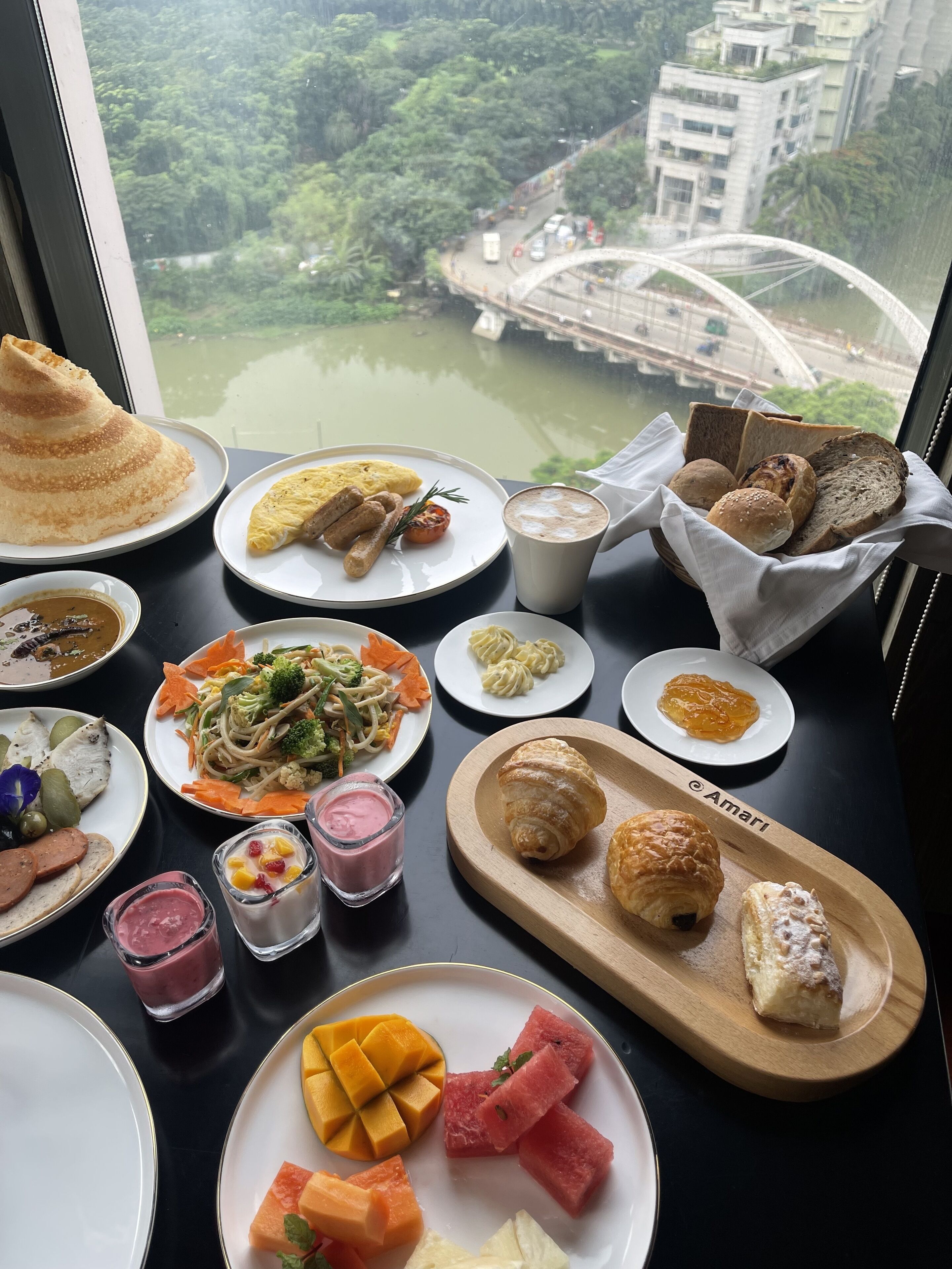 A table with various dishes and a view of a river and bridge.