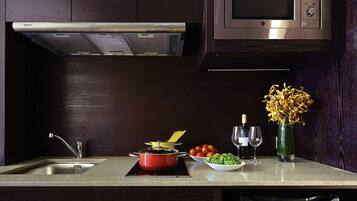 A kitchen with a microwave, stove, sink, and a vase with flowers.