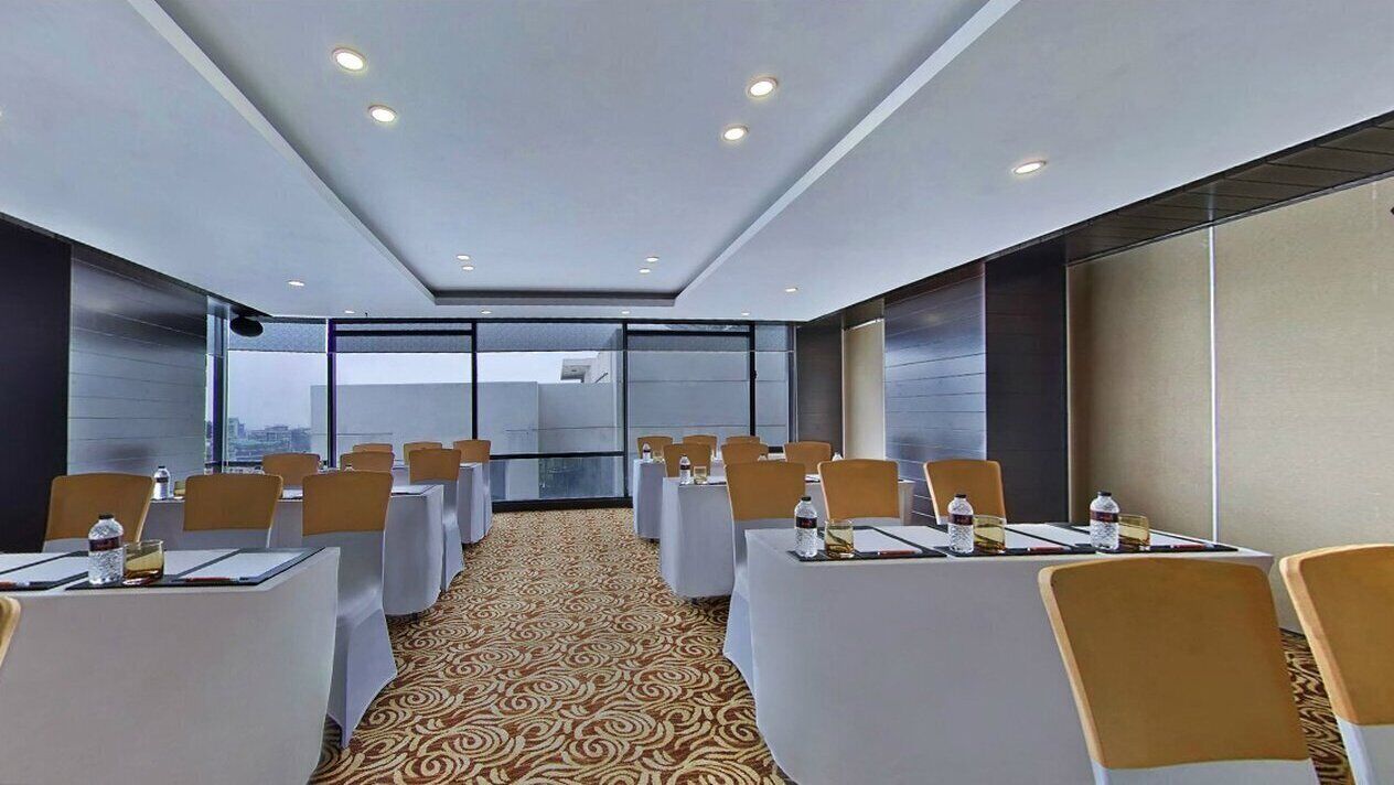 A conference room with tables and chairs, large windows, and a patterned carpet.