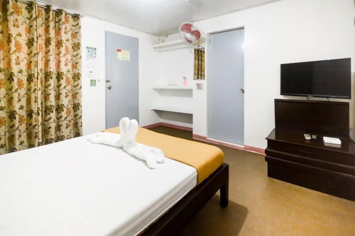 A hotel room with a bed, a television, a desk, and a wardrobe.