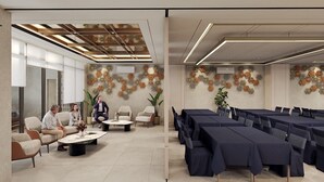 A modern conference room with a high ceiling, patterned wall decor, and a seating area with tables and chairs. - Laxston Hotel by Front One (Yogyakarta)