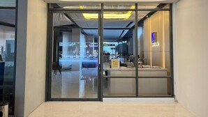 The entrance of the Laxston Hotel with a modern design, featuring glass doors and a well-lit interior visible through the glass. - Laxston Hotel by Front One (Yogyakarta)