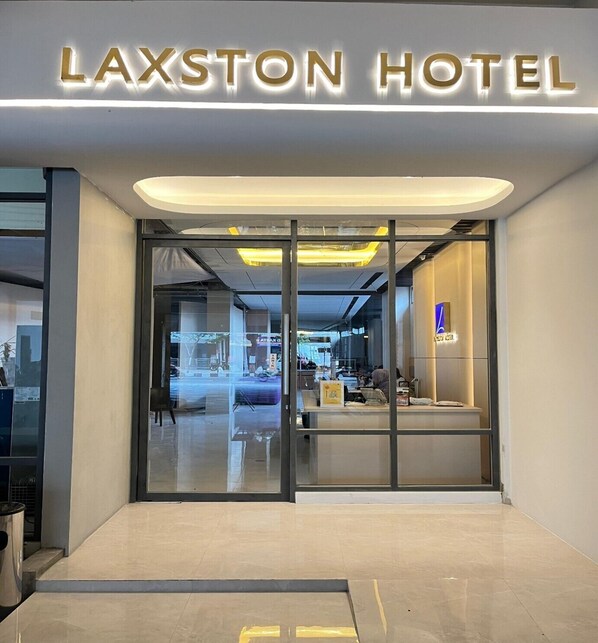 The entrance of the Laxston Hotel with a modern design, featuring glass doors and a well-lit interior visible through the glass. - Laxston Hotel by Front One (Yogyakarta)
