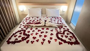 A hotel room with a large bed, white linens, and a modern abstract painting above the headboard. - Laxston Hotel by Front One (Yogyakarta)
