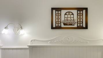 A bathroom with a white vanity, a wall-mounted light fixture, and a decorative piece above the mirror.