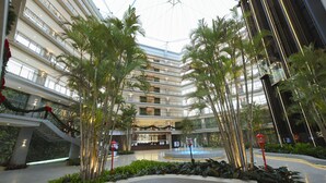 Un atrio de varios niveles con una fuente central, rodeado de palmeras y un diseño arquitectónico moderno.