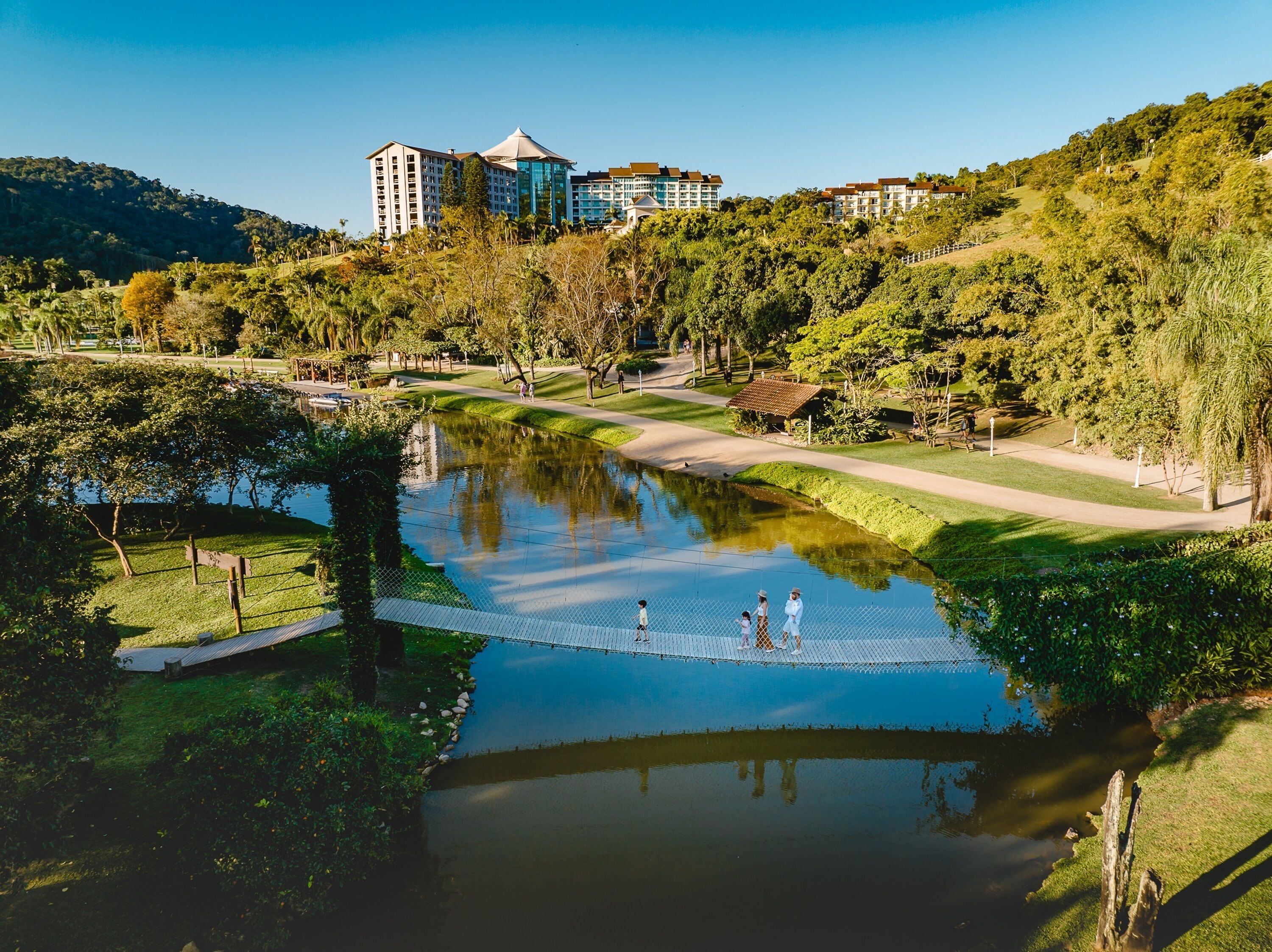 A serene park with a pond, walking paths, and a building complex in the background.
