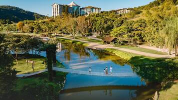 A serene park with a pond, walking paths, and a building complex in the background.
